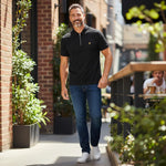 A man wearing a black Lyle & Scott quarter-zip polo shirt from WILDVINE Clothing Co. with blue jeans and sneakers.