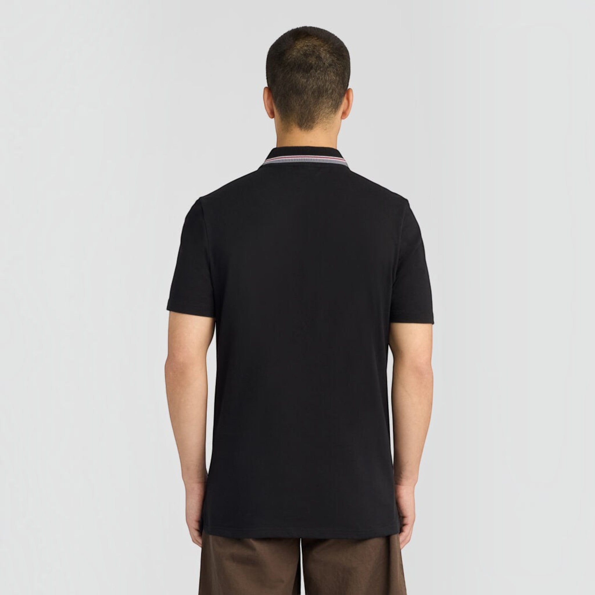 Back view of a man wearing a jet black WILDVINE Clothing Co. tipped track polo shirt with a striped collar.