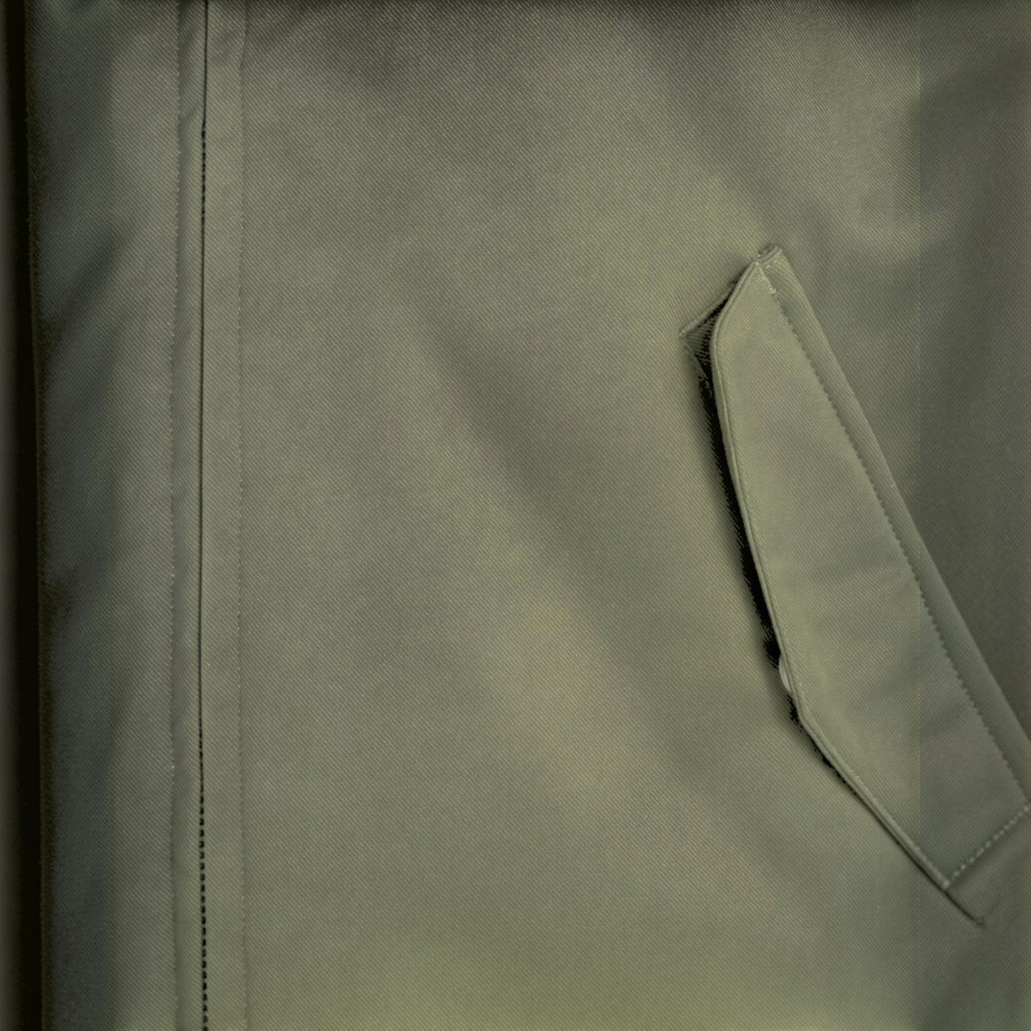 Close-up of a deep green padded jacket by WILDVINE Clothing Co. featuring a zippered pocket and durable fabric.