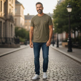 A man wearing a khaki ash Lyle & Scott crew neck t-shirt from WILDVINE Clothing Co. with blue jeans on a city street.